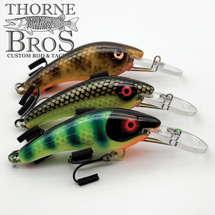 Three detailed Blue Water Baits 5" K.O. Shad fishing lures in brown, green, and blue patterns with treble hooks, displayed on a white background.