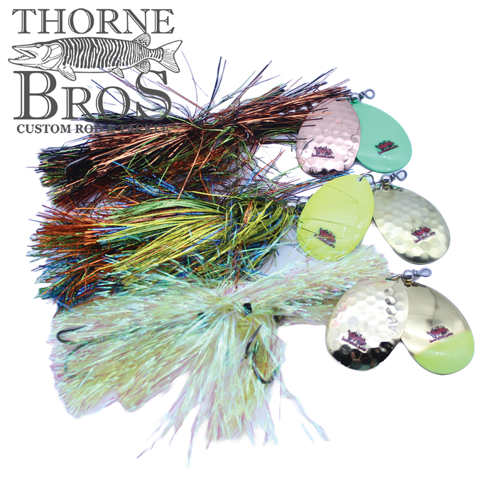 Close-up of four Blue Water Baits Show Stopper 11 fishing lures with colorful, reflective skirts and hammered metal spinner blades in various shades designed for musky fishing.