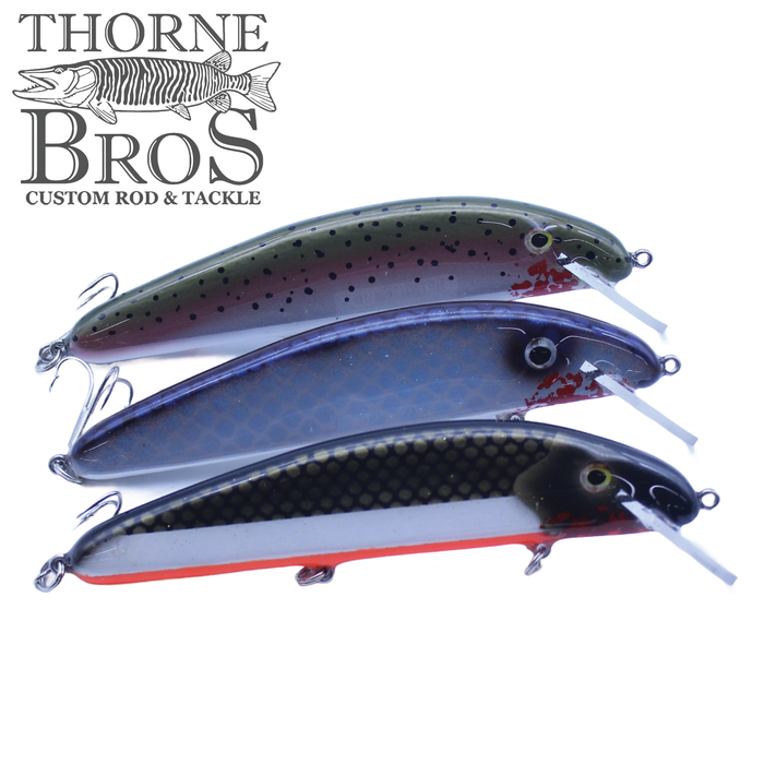 Three detailed fishing lures in green, blue, and black with red accents, each featuring hooks and clear diving lips, representing B&N Little Claw - 6.75" designed for musky fishing.