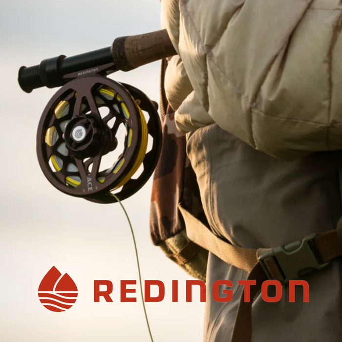 Close-up of a person holding a Redington fly fishing rod and reel, highlighting fishing tackle details for Bob Mitchell's Fly Fishing College.