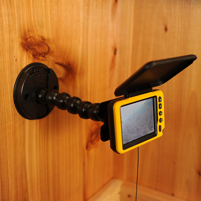 Catch Cover-Multi-Flex Camera Mount (Wall Mount) securely attached to a wooden wall, featuring a flexible arm holding a yellow, screen-equipped marine electronics device with a protective cover open, used for fishing tackle monitoring.