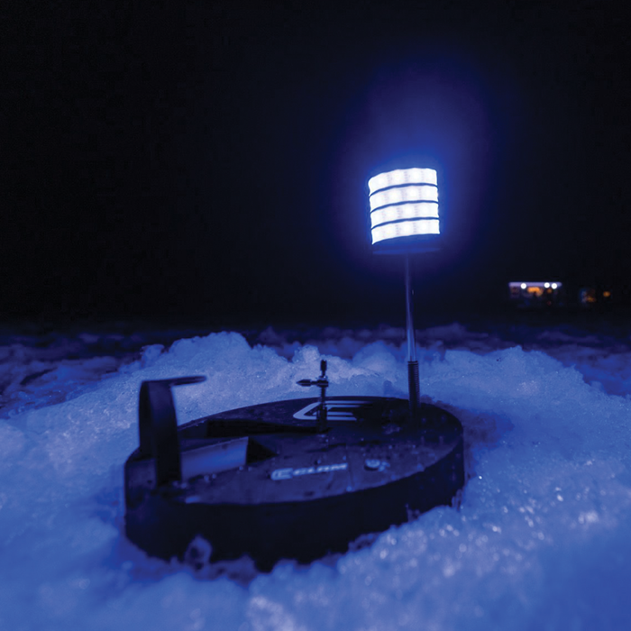 Clam Watchtower Lighted Tip-Up on ice, featuring bright LED lights mounted on a black base designed for ice fishing visibility in low-light conditions.