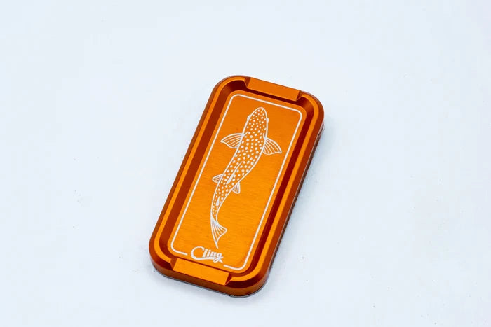 Cling Mag Grab Double Stack in orange with a fish illustration on top, designed as a compact, durable fishing tackle accessory for securely holding gear.