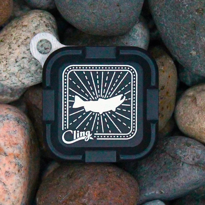 Black compact rectangular fishing tackle container with hinged lid, featuring a graphic fish design and the text Cling, identified as Cling Mag Grab Plus.