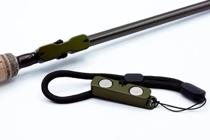 Cling Mag Grab Rod Rack in deep green attached to a fishing rod handle, featuring magnetic clips and a black adjustable cord for secure fishing tackle organization.
