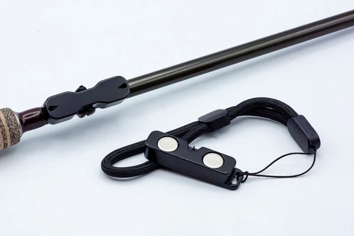 Cling Mag Grab Rod Rack shown attached to a fishing rod, featuring a black magnetic locking mechanism with a durable strap designed to securely hold fishing rods and tackle.