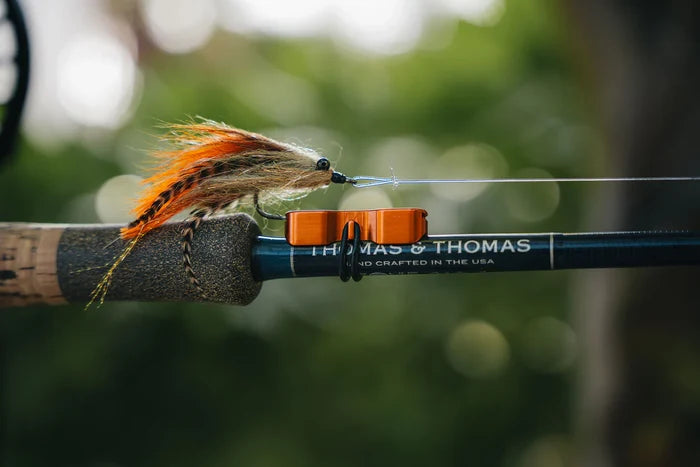Cling Mag Grab Rod Rack attached to a fishing rod holding a colorful fishing lure with natural outdoor background, suitable for organizing fishing tackle.