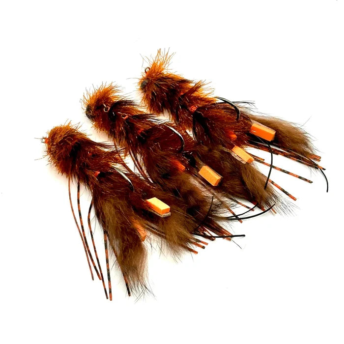 Close-up of four Craw Changer fishing lures featuring brown and orange feathers with hooks, designed for musky fishing and detailed for effective water movement.