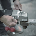 Person inserting key into a silver DuraSafe Coupler Lock 3" Pin installed on a metal hitch for securing a trailer or equipment connection.