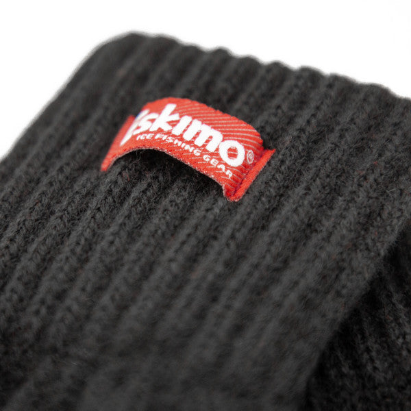Close-up of a black ribbed knit fabric with a red label showing the brand "Eskimo" on an Eskimo Fingerless Wool Glove, designed for cold-weather fishing and outdoor use.