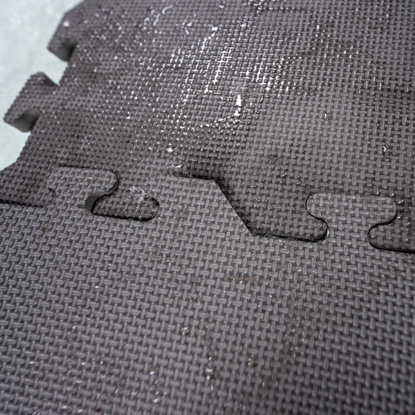Close-up of black interlocking textured foam tiles with water droplets on the surface showcasing the Eskimo Floor Tile Kits designed for durable, water-resistant flooring.