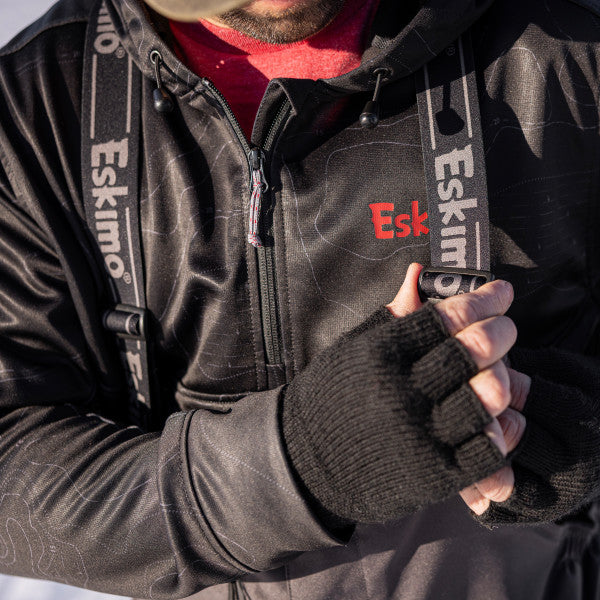Close-up of a person wearing the Eskimo Roughneck Bib - Men's in dark water-resistant material with adjustable branded suspenders, shown with black fingerless gloves.