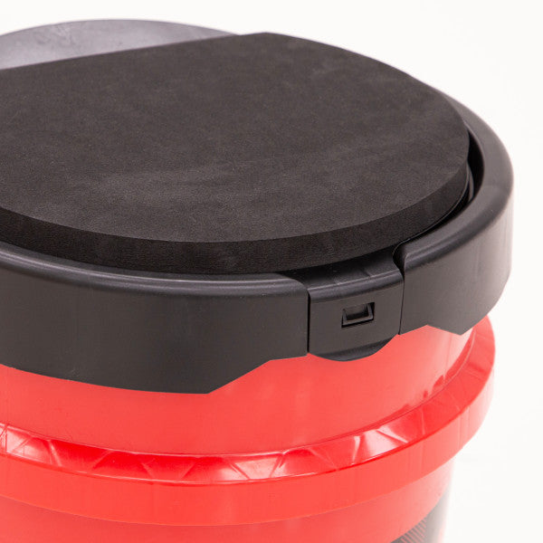 Close-up of a black Eskimo Seatstash Bucket Lid securely fitted on a bright red bucket, designed for fishing tackle storage and outdoor use.