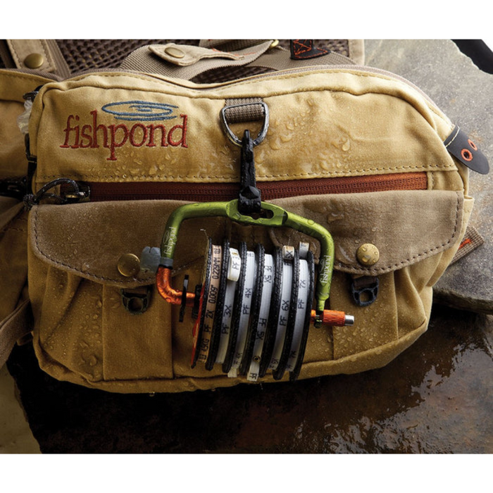 Fishpond Headgate Tippet Holder attached to a tan fishing vest, displaying multiple labeled tippet spools organized in a compact, durable frame for easy access during fishing.
