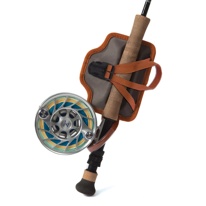 Fishpond Quickshot Rod Holder 2.0 in tan and gray secures a fly fishing rod with cork handle and silver reel, designed for convenient transport and storage in fishing tackle.