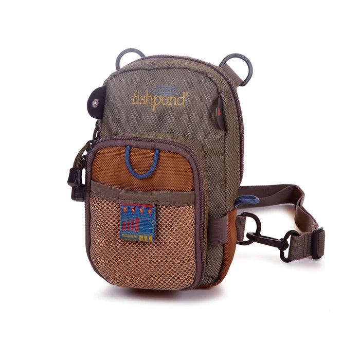Fishpond San Juan Chest Pack in earth-toned fabric with multiple zippered compartments, mesh pocket, side loop, and adjustable waist strap for hands-free fishing tackle storage.
