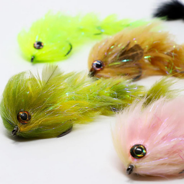 Four detailed fishing lures with lifelike eyes and feather-like textured bodies in green, brown, yellow, and pink colors, designed for use with the FlyMen PolarLite Changer.