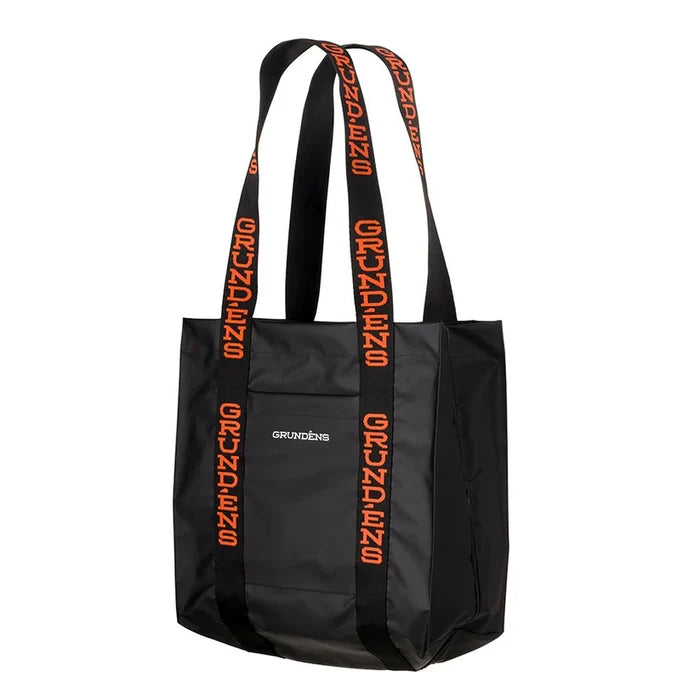 Grundens Shoreman Tote Bag in black with durable construction and long handles featuring orange Grundens branding, designed for carrying fishing tackle and gear.