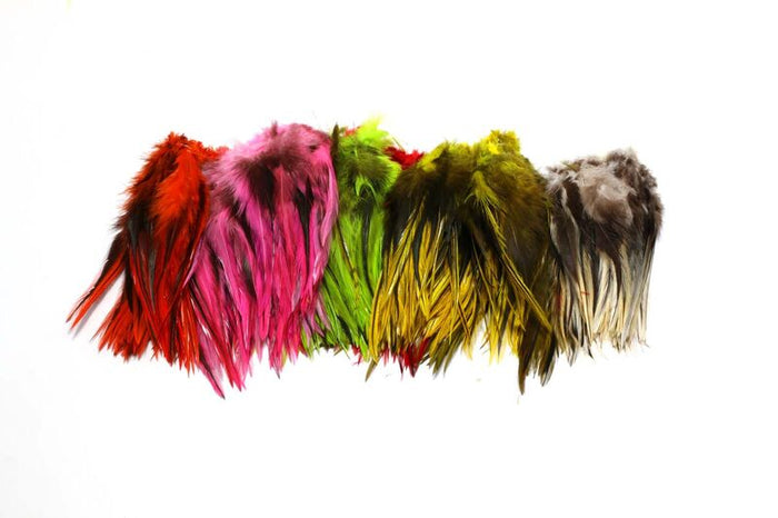 Hareline Badger Saddle Hackle feathers in a variety of vibrant colors including red, pink, green, yellow, and natural brown, used for fly fishing tackle and lure tying.