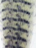 Close-up image showing a pattern resembling natural grizzly feathers in muted beige and black tones, representing Hareline Grizzly Fibre used in fly fishing tackle.