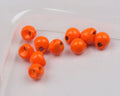 Close-up of bright orange Hareline Insta-Jig Tungsten Head fishing tackle components, designed for use with custom fishing rods and lures.