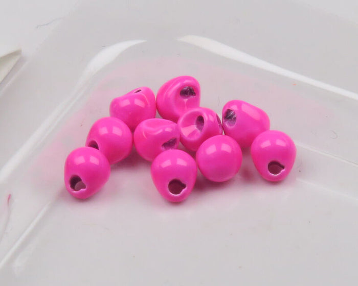 Close-up of several bright pink Hareline Insta-Jig Tungsten Head fishing jig heads designed for use with musky tackle and fishing lures.