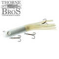 Livingston Lures Kraken fishing lure with a sleek, white hard body and soft, segmented skirt designed to attract musky and other large game fish, equipped with sharp treble hooks.