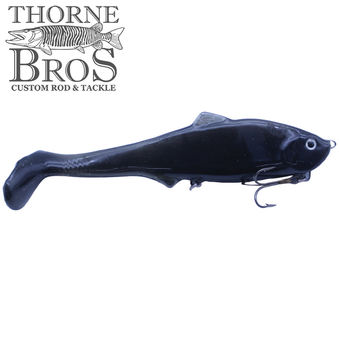 Black soft plastic fishing lure shaped like a small fish with a curled tail and a treble hook underneath, designed for musky fishing, labeled Llungen $ Maker.