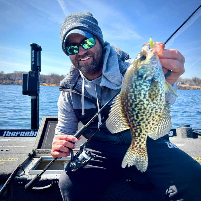 Man wearing sunglasses and a beanie holding a crappie fish caught using the Matt Johnson Outdoors - OW Crappie Rod *4 Week Build Time on a boat with a clear blue sky in the background.