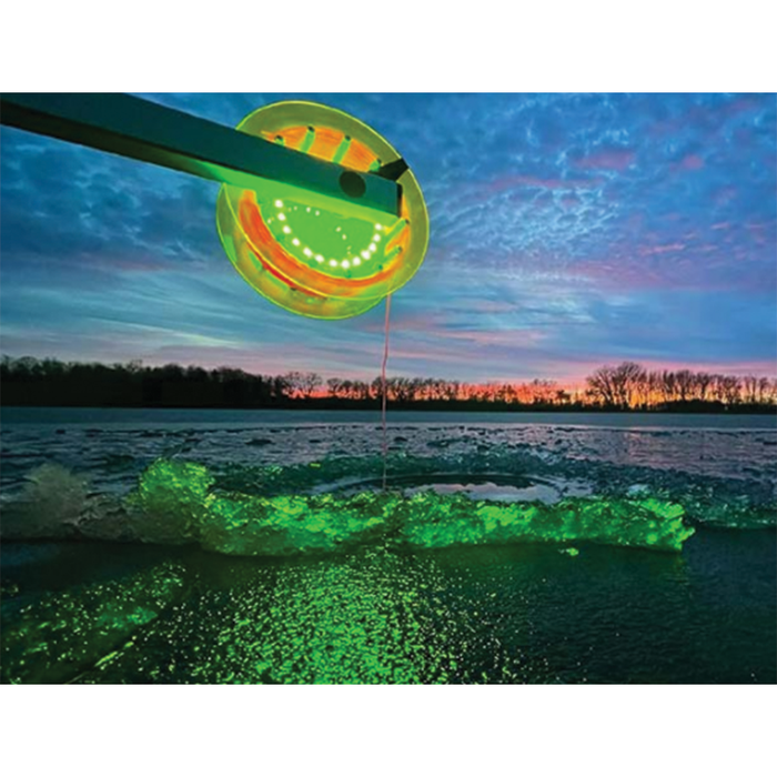 Northern Lights Lighted Rattle Reel glowing green as it suspends fishing line over ice at dusk, highlighting a scenic lakeside background with a colorful sky.