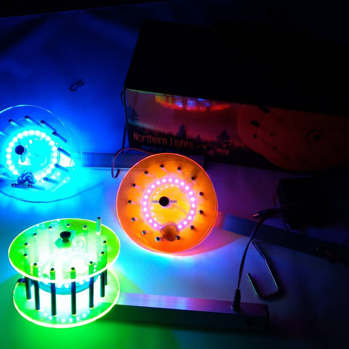 Northern Lights Lighted Rattle Reel fishing tackle glowing in blue, orange, and green light alongside a branded box, showcasing its illuminated design for enhanced visibility.