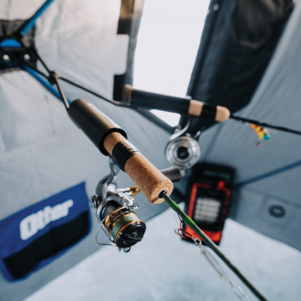 Otter QA Dual Rod Holder securely holds two fishing rods with reels attached inside a fishing shelter, featuring cork handles and metal reel seats for fishing tackle organization.