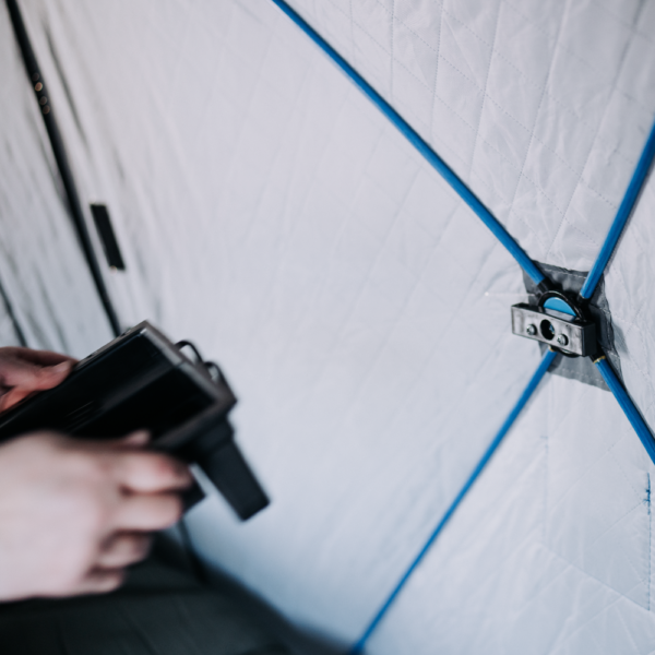 Close-up of hands securing the blue bungee cords on the Otter QA Multi-Shelf, showing its durable quilted fabric and metal attachment used for organizing fishing gear.