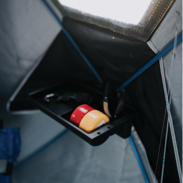 Otter QA Multi-Shelf mounted inside a tent, showing a compact black plastic tray holding a flashlight and small items, designed for convenient storage in fishing or outdoor gear setups.