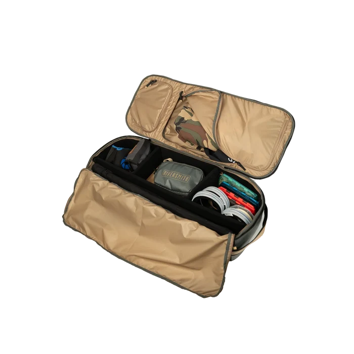 Riversmith Convoy Travel Pack in tan, open to show organized compartments with tackle boxes, gear pouches, and fishing accessories for convenient fishing tackle storage.