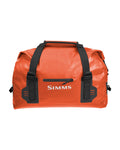 Simms Dry Creek Duffel in bright orange with black straps, featuring a front zipper pocket and durable waterproof material designed for fishing tackle and gear storage.