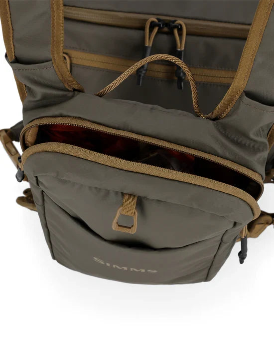 Simms Headwaters Chest Pack in olive green with tan trim, shown open to reveal multiple compartments and heavy-duty zippers designed for durable outdoor fishing use.