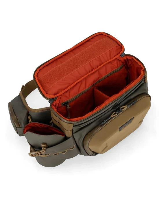 Simms Headwaters Hip Pack in olive and tan with multiple zippered compartments and padded orange interior, designed for organized fishing tackle storage.