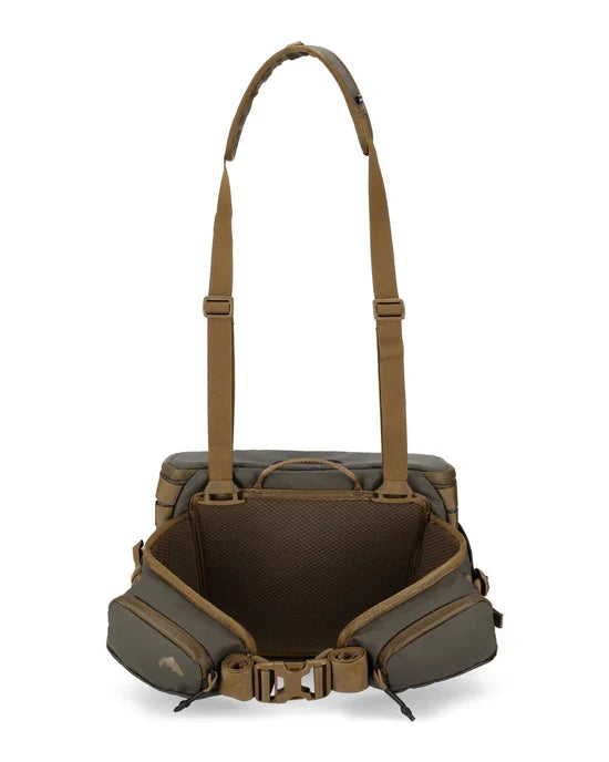 Simms Headwaters Hip Pack in olive green and tan, featuring multiple zippered pockets, adjustable padded suspenders, and breathable mesh waist support for fishing tackle storage.
