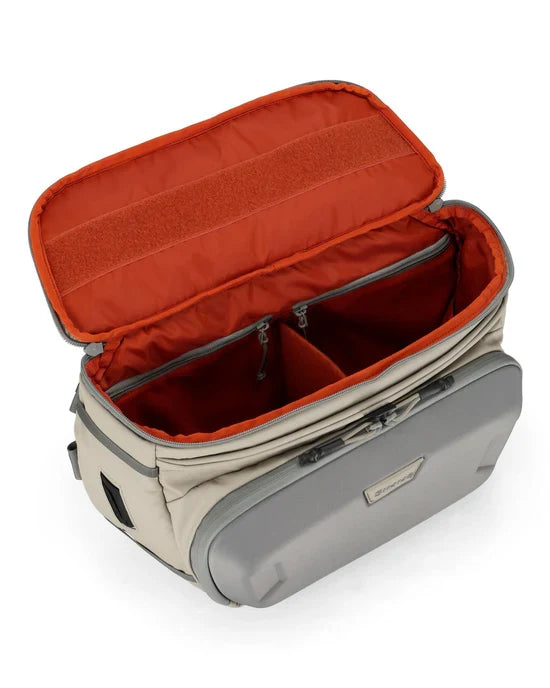 Simms Headwaters Sling Pack in beige with orange interior, showing spacious main compartment with zipped dividers and exterior pocket designed for organized fishing tackle storage.