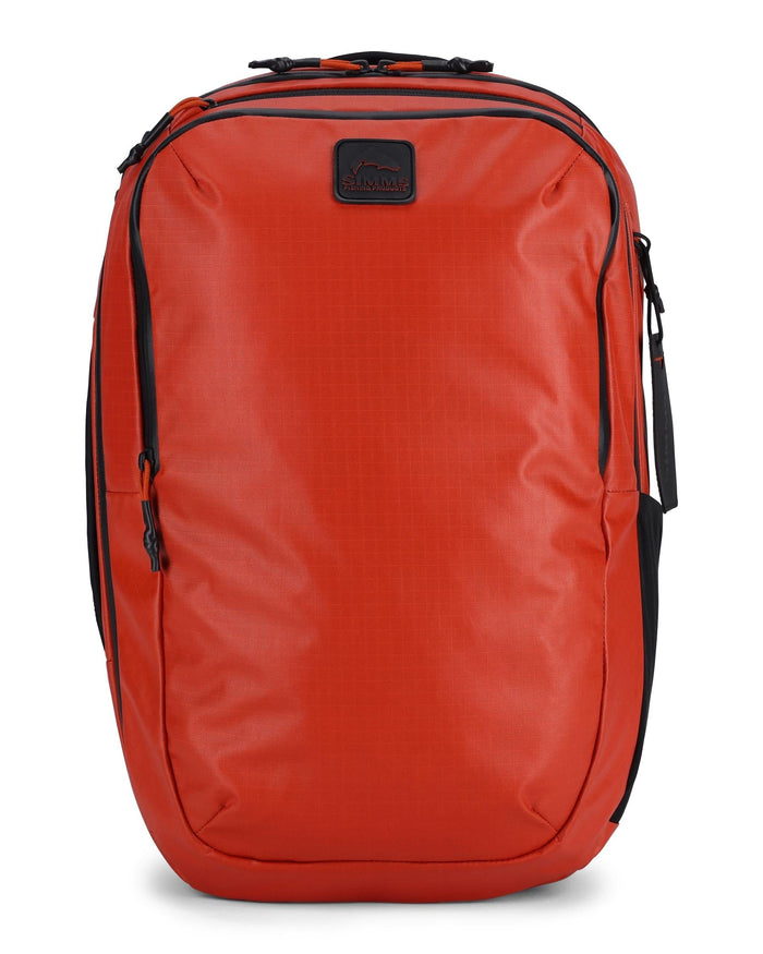 Simms Tailwind Backpack in bright orange with multiple zippered compartments, a black logo patch on the front, padded shoulder straps, and a sleek, durable design ideal for fishing tackle and outdoor use.