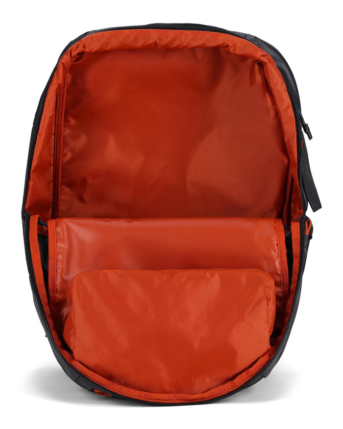Simms Tailwind Backpack open to show spacious main compartment with bright orange interior lining designed for organizing fishing tackle and gear.