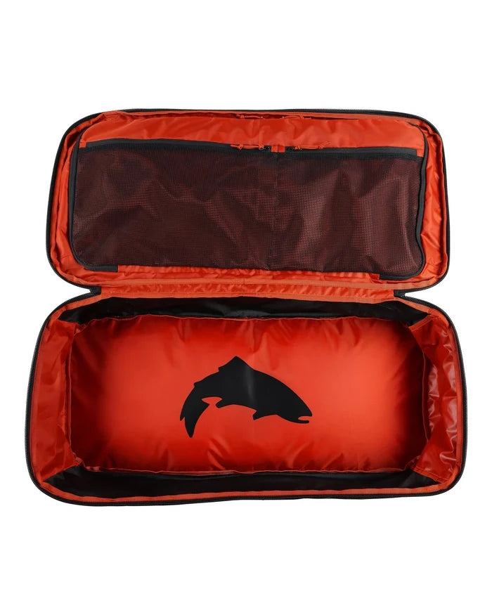 Open Simms Tailwind Duffel 80L showing spacious bright orange interior with black fish silhouette and a mesh zippered pocket inside the lid for organized storage.