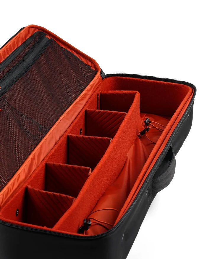 Simms Tailwind Rod & Reel Vault with black exterior and bright orange padded interior, featuring adjustable compartments for secure fishing rod and reel storage.