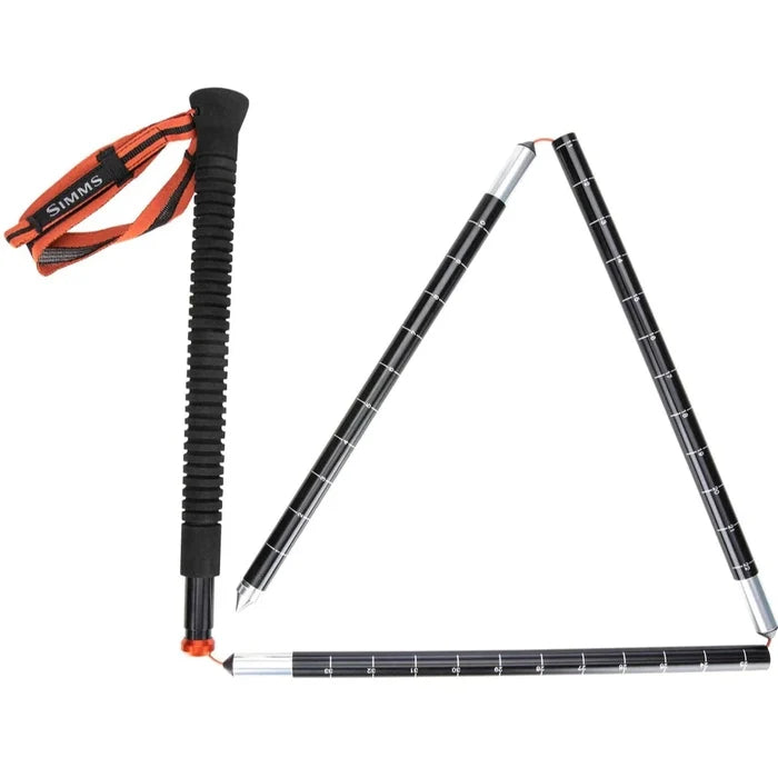 Simms Wading Staff made of carbon material, featuring a textured black grip with an orange wrist strap, shown partially unfolded with measurement markings on the shaft.