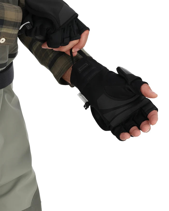 Close-up of a person wearing black Simms Windstopper Foldover Mitt gloves with fold-back fingers, adjustable wrist strap, and textured grip, suited for fishing and outdoor activities.