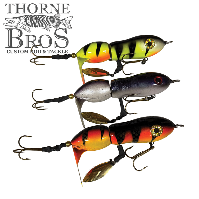 Three Snaggle Tooth Tackle Mini Beast Prop Bait fishing lures in yellow with black stripes, silver with dark blue back, and red with black stripes, each featuring multiple treble hooks and metal propellers.