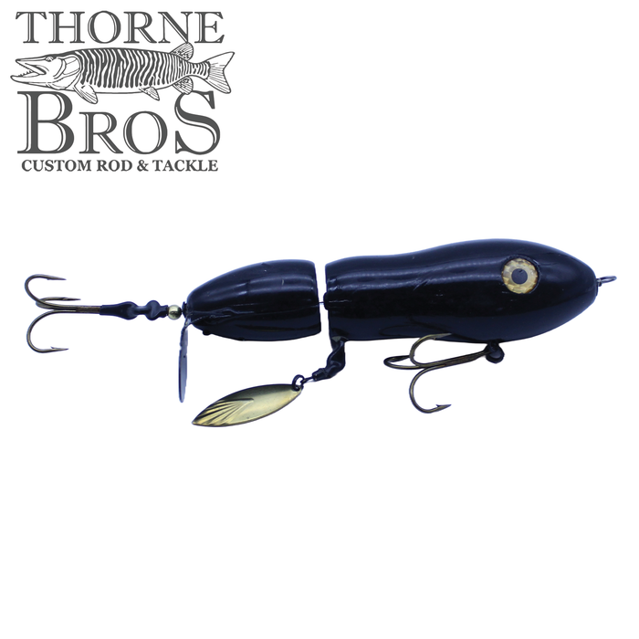 Snaggle Tooth Tackle Super Beast Prop Bait in black with jointed body, metal spinner blade, and treble hooks, designed for musky fishing by Thorne Bros.