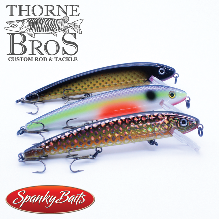 Three detailed fishing lures in black, silver with red accents, and brown with a scale pattern, displayed with Spanky Baits M Series Pro (M7 & M9) branding and Thorne Bros logo for fishing tackle and lures.