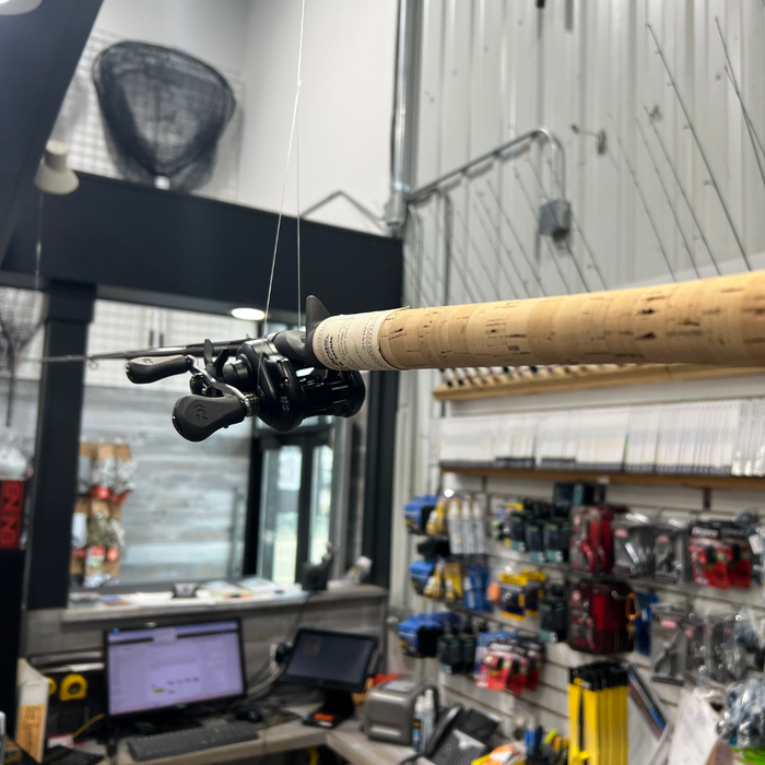 A fishing rod and reel setup hanging in a store with various fishing tackle items in the background.